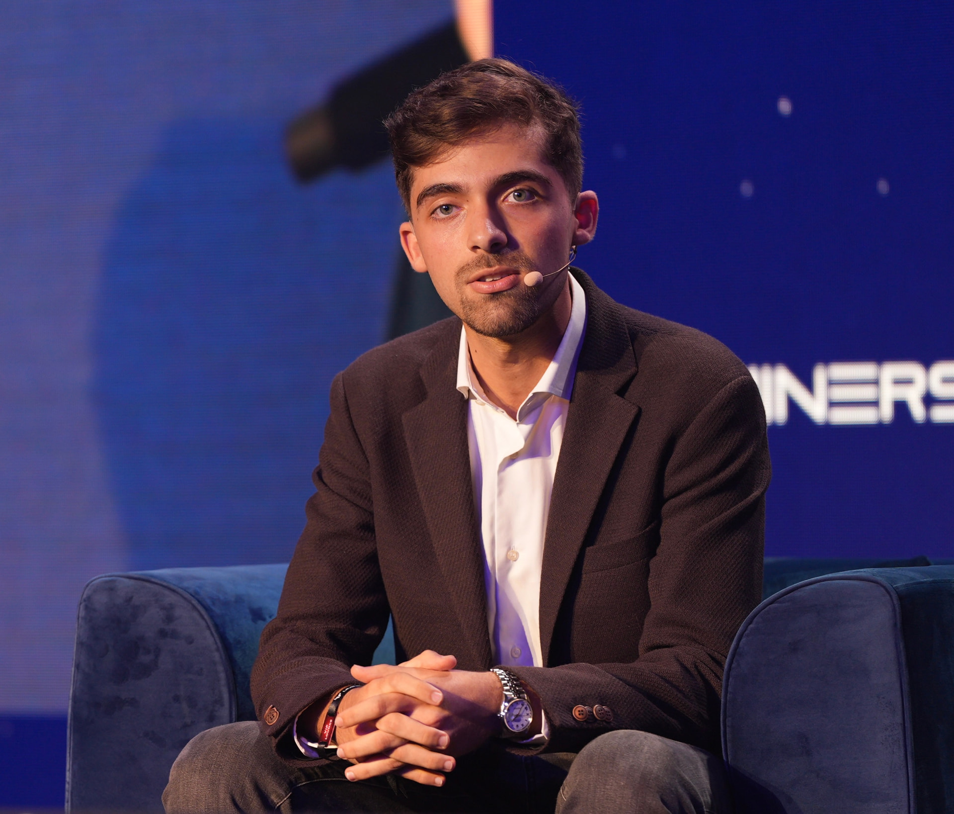 Efe Kelemci speaking on stage at a blockchain conference today